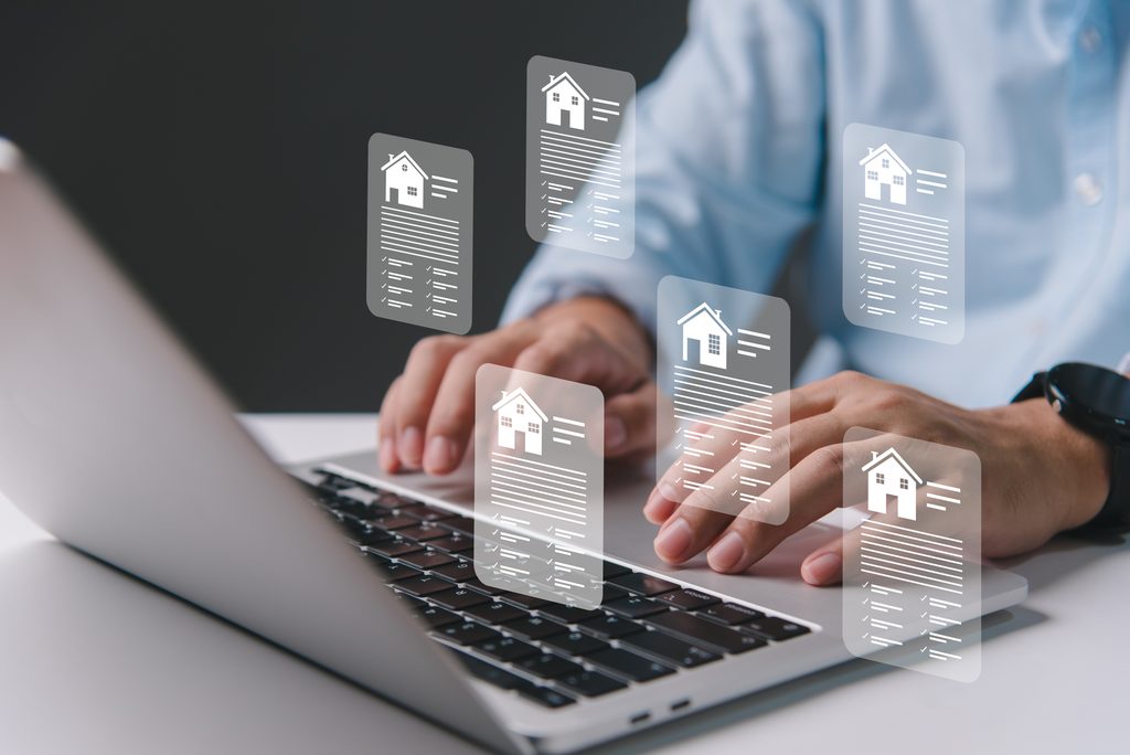 Professionnel de l’immobilier consultant des annonces de biens immobiliers sur ordinateur, illustrant les métiers de la transaction et de la gestion immobilière.